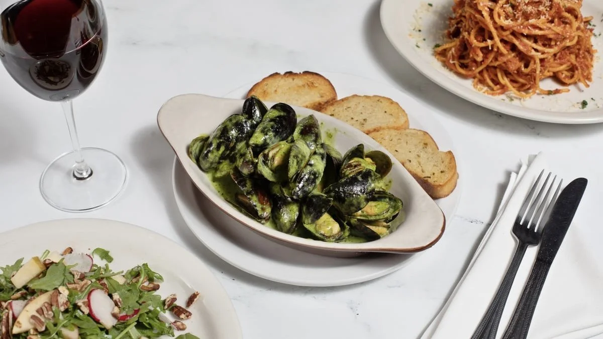 Mussels, pasta, salad, and wine set for sharing